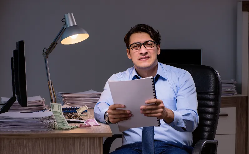 Stressed man holding loan papers, worried about increasing loan balance